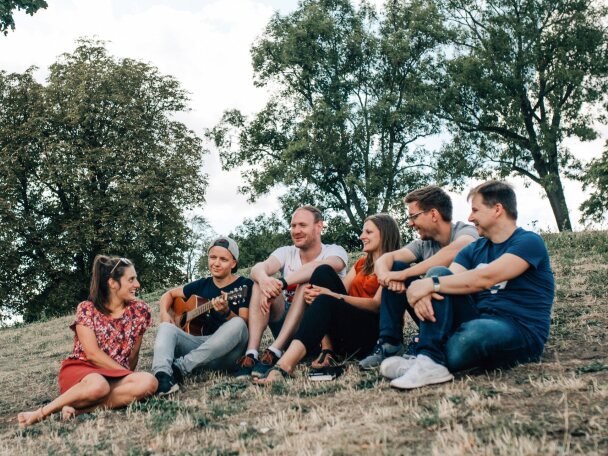 Eine Gruppe junger Menschen sitzt auf einer Wiese im Kreis